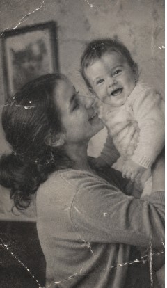 Torn, faded photo of a mother holding her laughing baby before AI restoration